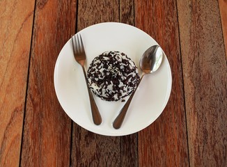  White and black Steamed rice or boiled rice In a white plate placed on a wooden table.