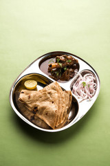Mini chicken curry Thali with chapati/roti, popular indian lunch/dinner menu. served in a stainless steel oval plate with salad. selective focus