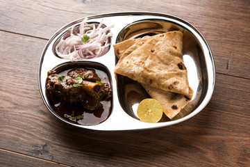 Mini chicken curry Thali with chapati/roti, popular indian lunch/dinner menu. served in a stainless steel oval plate with salad. selective focus