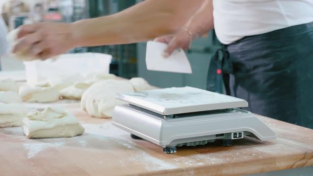 Professional baker divides the dough into portions and weights them