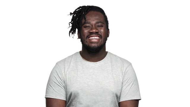 Portrait of vivacious african american man with big smile laughing and expressing joy, isolated over white background slow motion. Concept of emotions