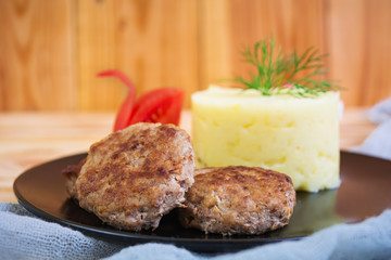 Puree potatoes with cutlets on wooden background