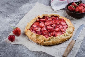 Delicious summer food dessert. Galette with strawberry on the gray concrete stone background.