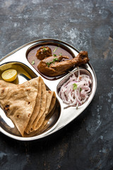 Mini chicken curry Thali with chapati/roti, popular indian lunch/dinner menu. served in a stainless steel oval plate with salad. selective focus