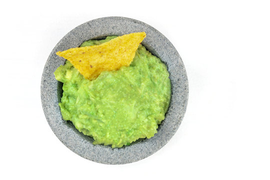 A photo of guacamole sauce in a molcajete, traditional Mexican mortar, on white