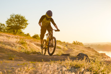 Fototapeta na wymiar Cyclist Riding the Mountain Bike on the Summer Rocky Trail at the Evening. Extreme Sport and Enduro Cycling Concept.