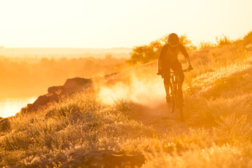Cyclist Riding the Mountain Bike on the Summer Rocky Trail at the Evening. Extreme Sport and Enduro...