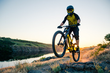 Cyclist Riding the Mountain Bike on the Summer Rocky Trail at the Evening. Extreme Sport and Enduro Cycling Concept.