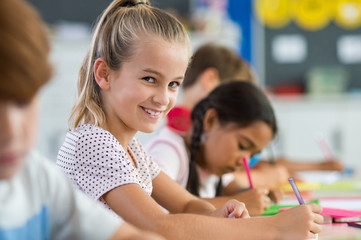 Obraz na płótnie Canvas Smiling girl doing classwork