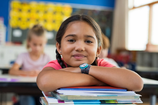 Hispanic girl with chin on books - Powered by Adobe