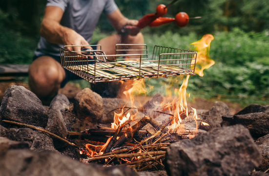 Summertime leisure concept image: man cooks a vegetabels on campfire
