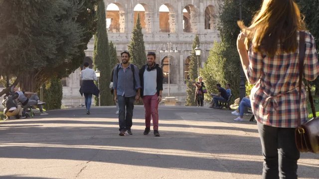 Young happy gay couple walk in park road with trees colosseum in background in rome at sunset holding hands lovely slow motion colle oppio