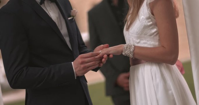 Bride and groom exchanging wedding rings and holding hands