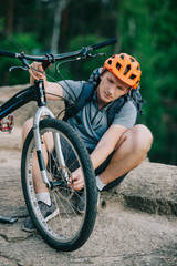 Obraz premium handsome young trial biker attaching wheel to bicycle outdoors