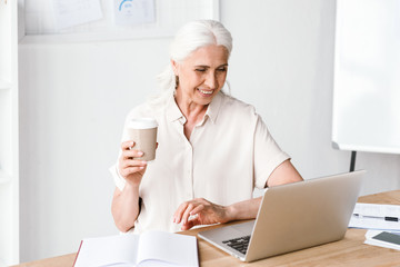 Smiling mature business woman working on laptop