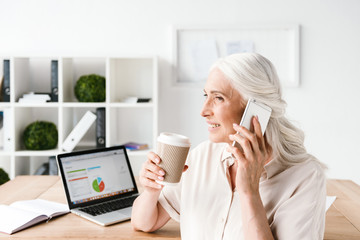 Cheerful mature business woman talking on mobile phone