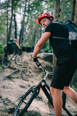 active young trial bikers riding uphill at beautiful pine forest