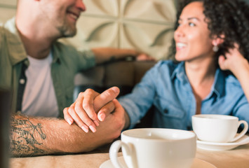 Happy young couple is drinking coffee and smiling while sitting at the cafe