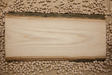 Piece of raw wood on chickpea background. Top view, space for text.