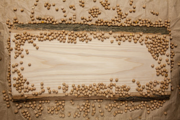Piece of raw wood with chickpea on crumpled brown paper background. Top view, space for text.