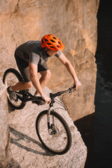 Naklejka premium high angle view of young trial biker balancing on rocks outdoors