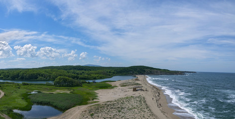 Curved coastline. Sand beach. Blue sea and waves. Sunny day.