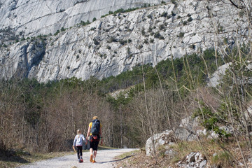Mutter mit Kind geht auf Felswand zu, Wandern in Italien