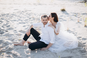 beautiful woman kissing her boyfriend while sitting on beach