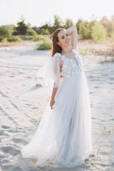Fototapeta na wymiar attractive woman in white dress posing on beach
