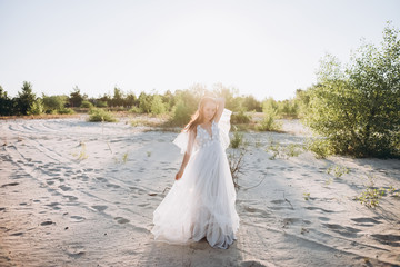 Fototapeta na wymiar beautiful young woman in white dress posing on beach with sunlight