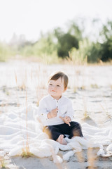 adorable baby boy sitting on blanket on beach