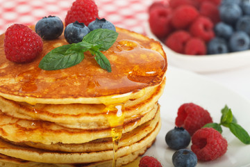 Homemade american buttermilk pancakes, served with fresh blueberries, rasberries and honey