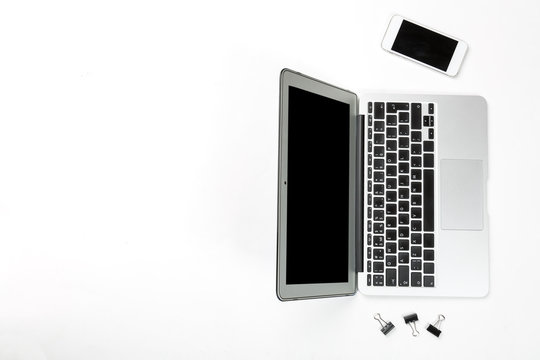 Conceptual workspace or business concept. Laptop computer with mobile cellular phone and black paper clips on white background. Top view with free space for your text