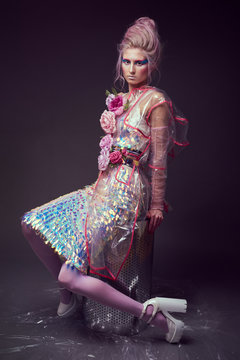 Gorgeous woman in biofuture pompadour style. Female in fashion transparent raincoat with splendid make up and hairstyle