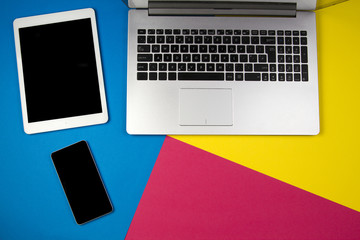Laptop computer, tablet and mobile phone on colorful background.