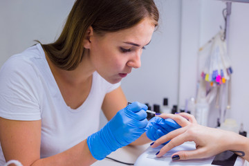 Manicurist master makes manicure on young woman hand