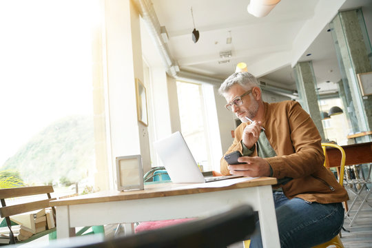 Man In Trendy Coffee Shop Working On Laptop Computer