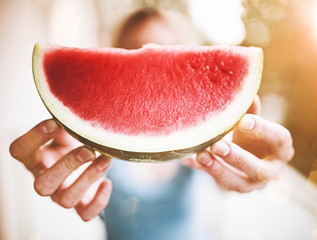front view of blond woman holding a slice of juicy fresh watermelon