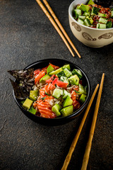 Asian trendy food, sushi poke bowl with cucumber, salmon, avocado, Black and White Sesame Seeds