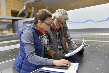 Industrial woodwork technicians reading blueprint