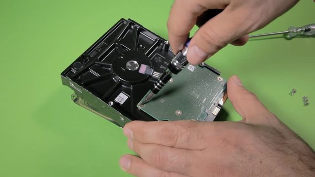 Unscrewing and removing the controller from a broken hard disk drive.
