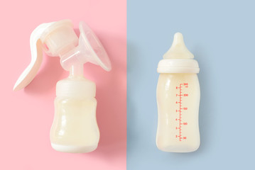 Breast pump and bottle of milk for newborn baby over pink and blue pastel colors background. Maternity and baby care concept. Girl or boy. Top view. - 209701104
