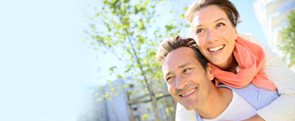 Man giving piggyback ride to woman in park, template