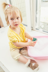 child on the windowsill washes the window