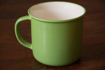 Green china cup on a wooden table. Close up.