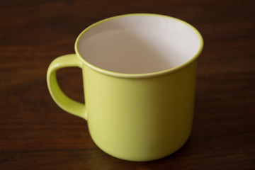 Yellow mug on a wooden table. Isolated.