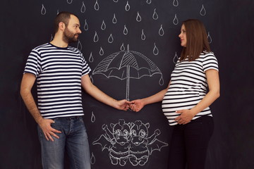 pregnant couple drawing their imaginations on chalk board