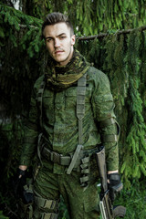 Fototapeta premium Young male military soldier with a rifle posing outdoors