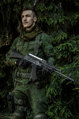 Young male military soldier with a rifle posing outdoors