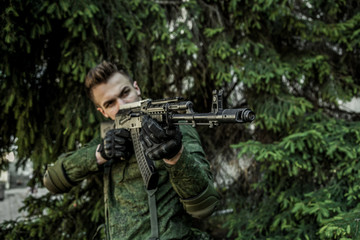 Fototapeta premium Young male military soldier with a rifle posing outdoors